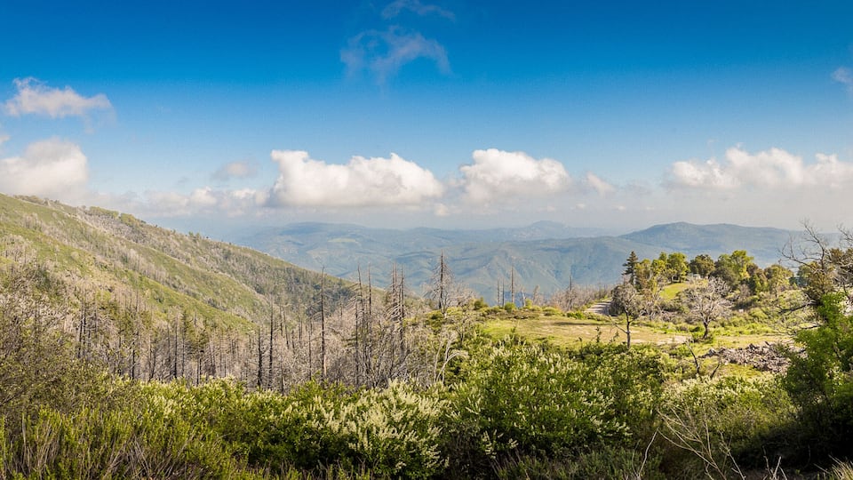 A mountainous landscape with green vegetation and a clear blue sky.