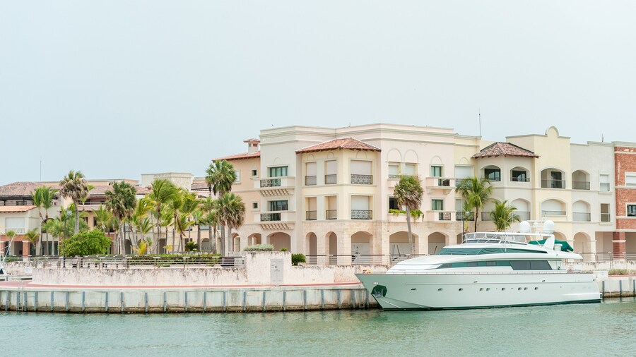 Punta Cana Architecture with port and Private Yacht. Dominican Republic. Luxurious Waterfront Residences With Yacht Docked Alongside Lush Palm Trees