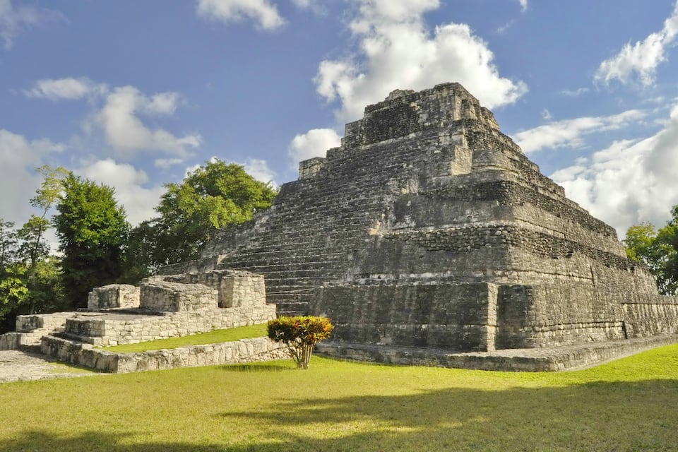 A large pyramid structure surrounded by grass and trees.