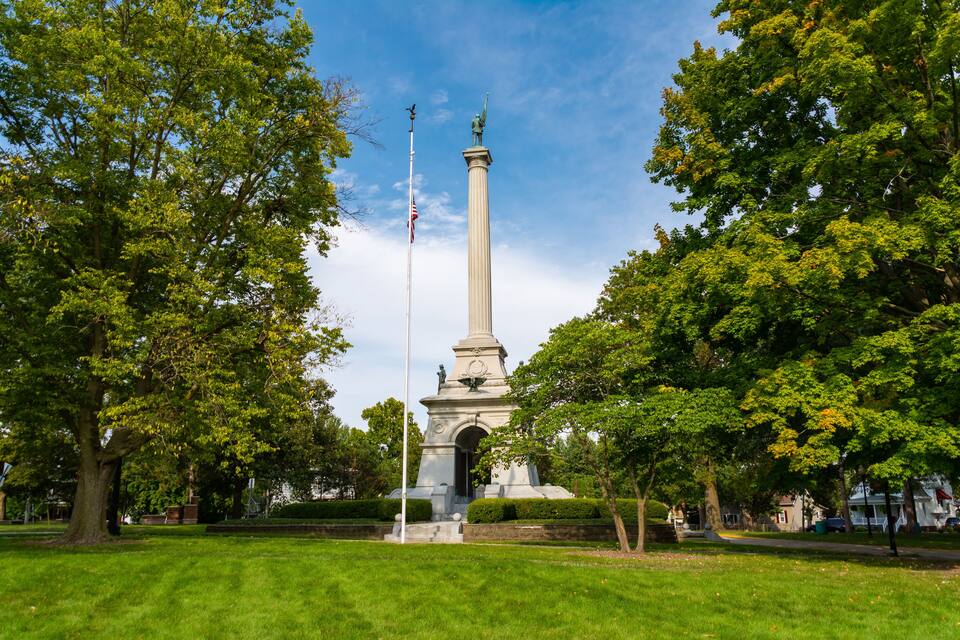 A tall monument surrounded by lush green trees in a park.