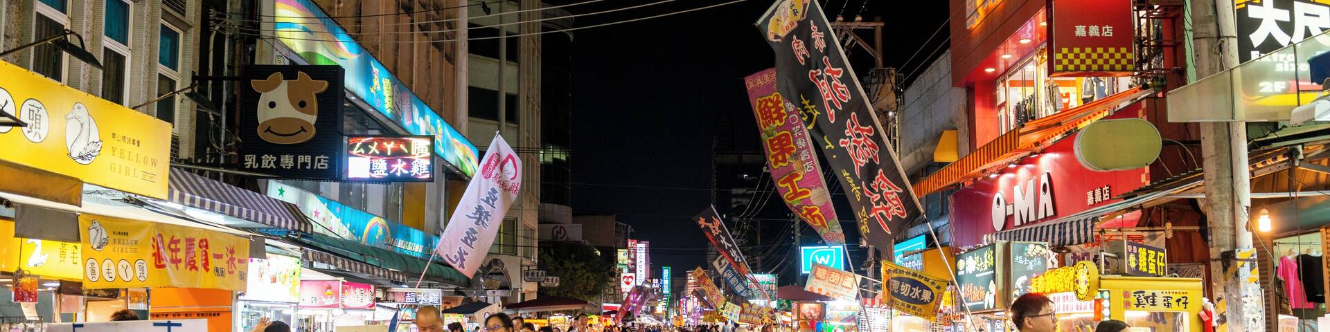 Una calle concurrida de noche, con letreros y comercios iluminados.