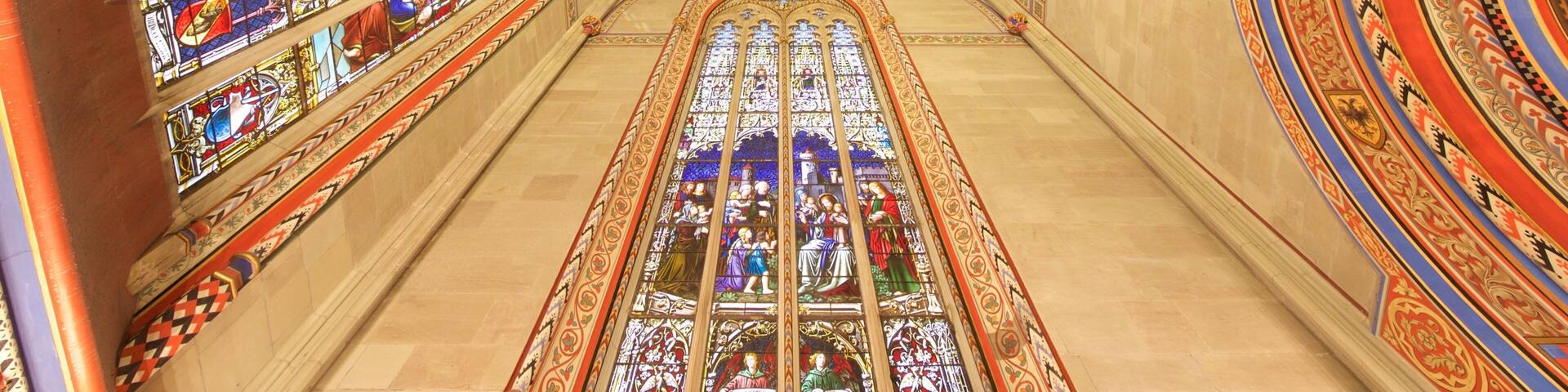 A cathedral interior with ornate stained glass windows and a detailed ceiling.