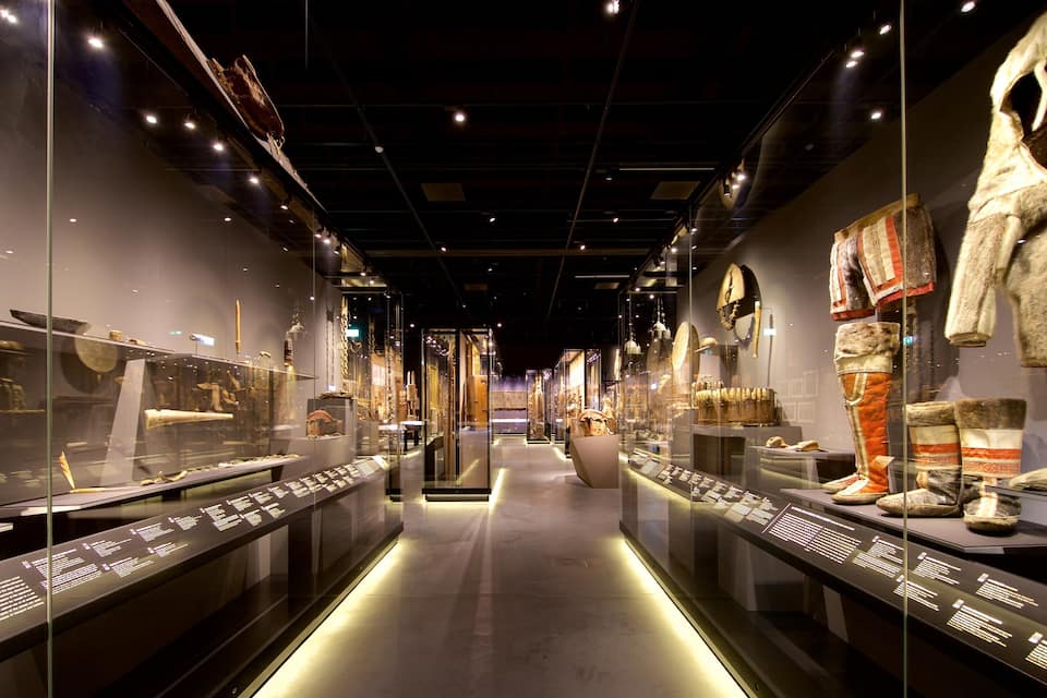 Een museumzaal met glazen vitrines vol objecten en informatieborden.