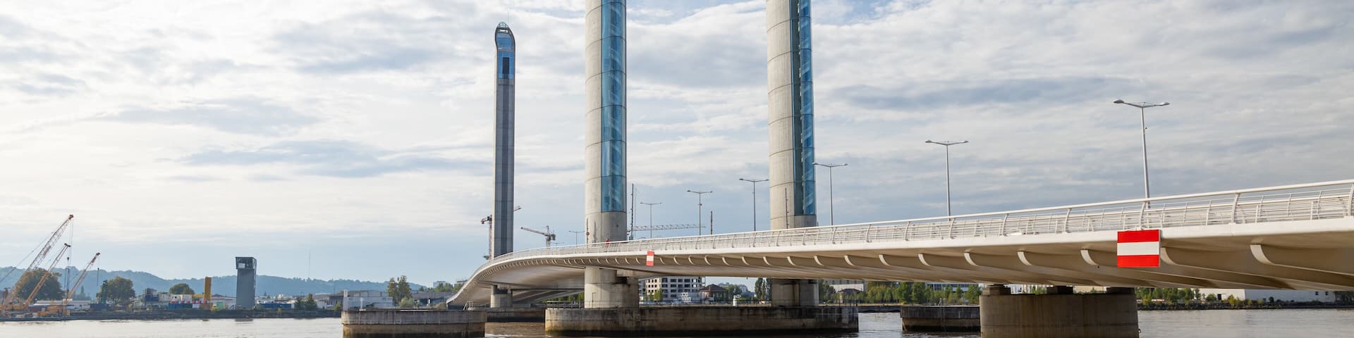 Un puente moderno con tres altos pilares cruzando un río.