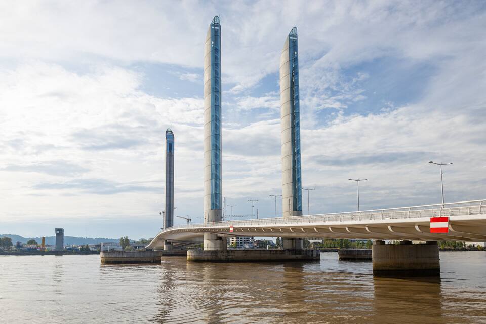A modern bridge with three tall pillars over a river.