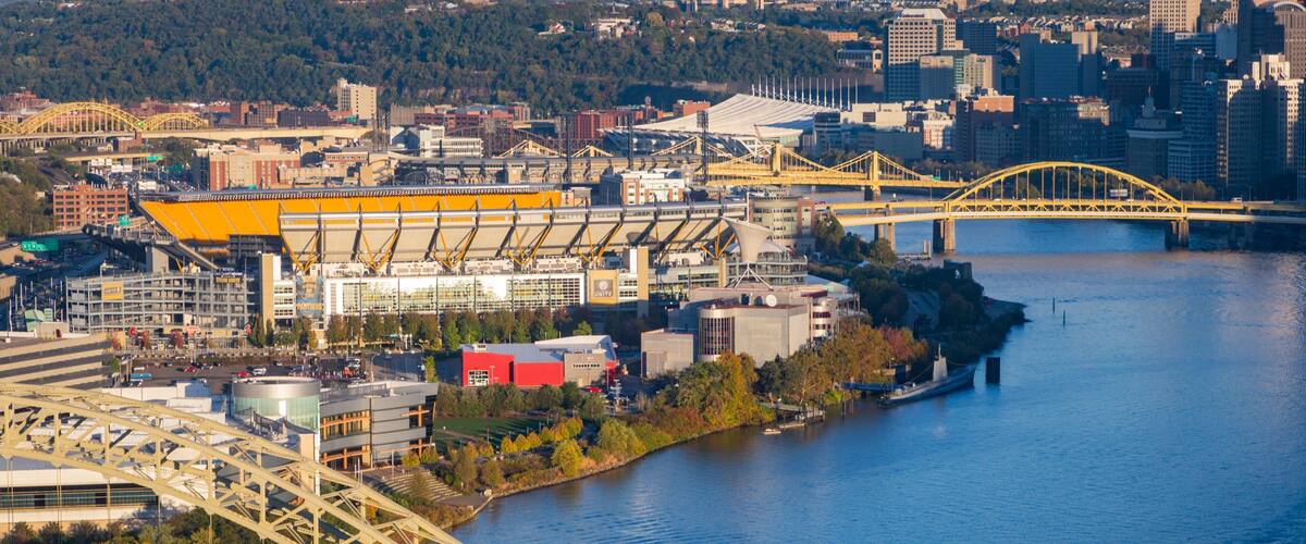 Ein Fluss mit einer Brücke, einem Stadion und einer Stadtlandschaft im Hintergrund.