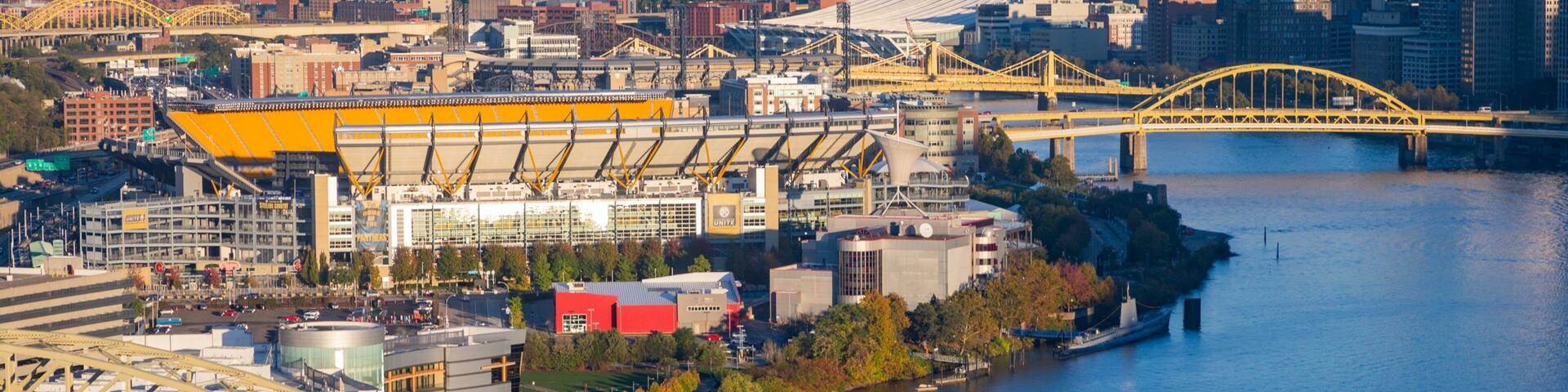 A river with a bridge, a stadium, and a cityscape in the background.