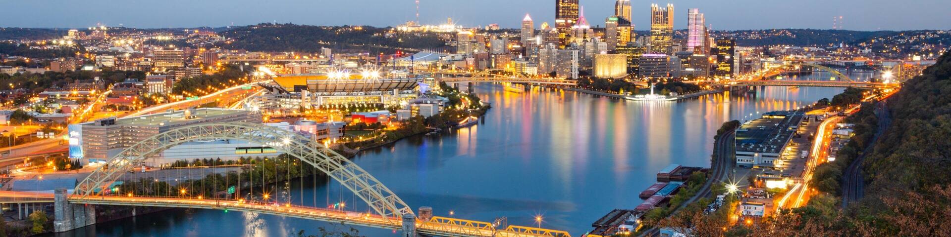 A cityscape with a river, bridges, and illuminated buildings.