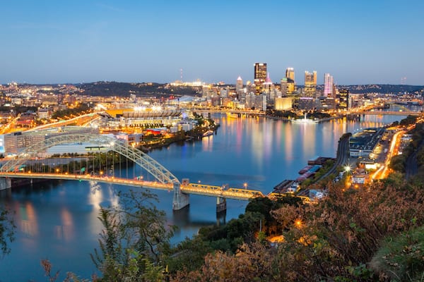 Une vue urbaine avec une rivière, des ponts et des bâtiments illuminés.