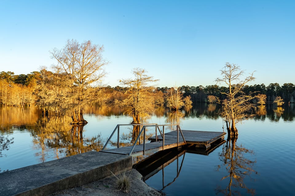 A wooden dock extending into a calm lake surrounded by trees.
