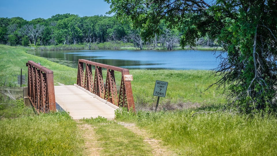 A bridge over a lake with a weight limit sign.