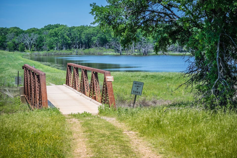 A bridge over a lake with a weight limit sign.