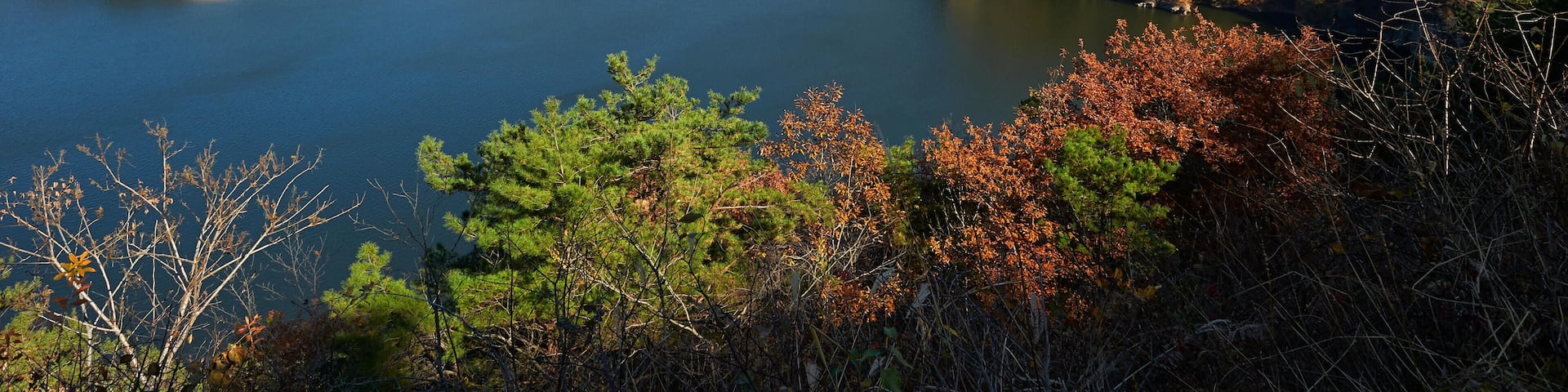 Un lago rodeado de árboles de colores otoñales y acantilados rocosos.