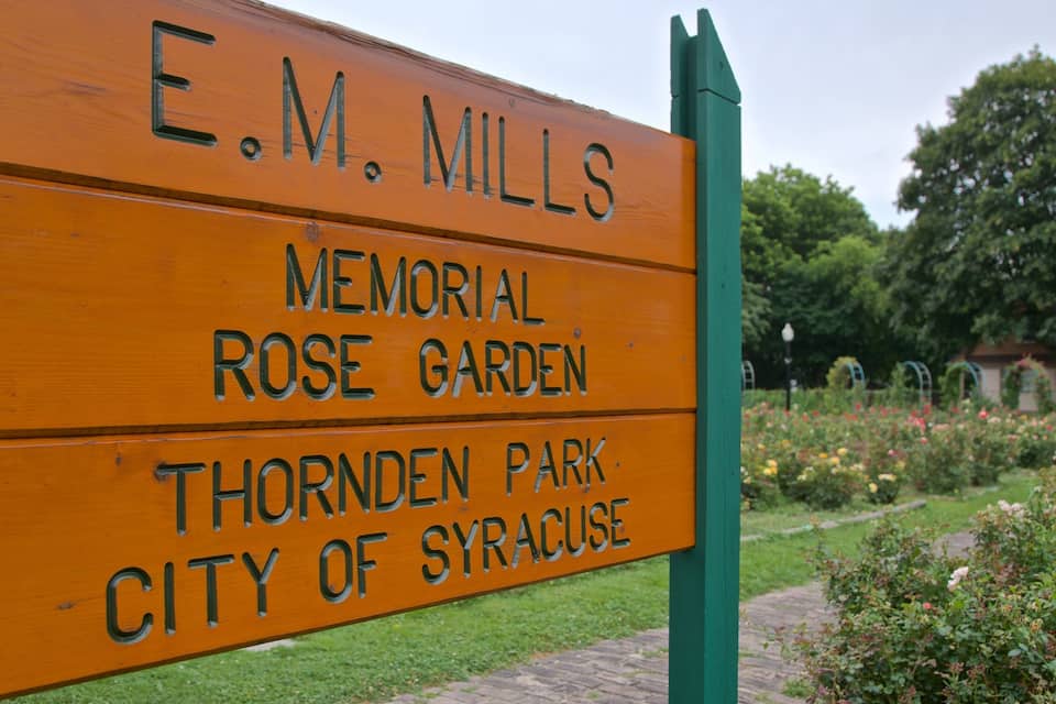 A wooden sign for E.M. Mills Memorial Rose Garden in Thornden Park, City of Syracuse.