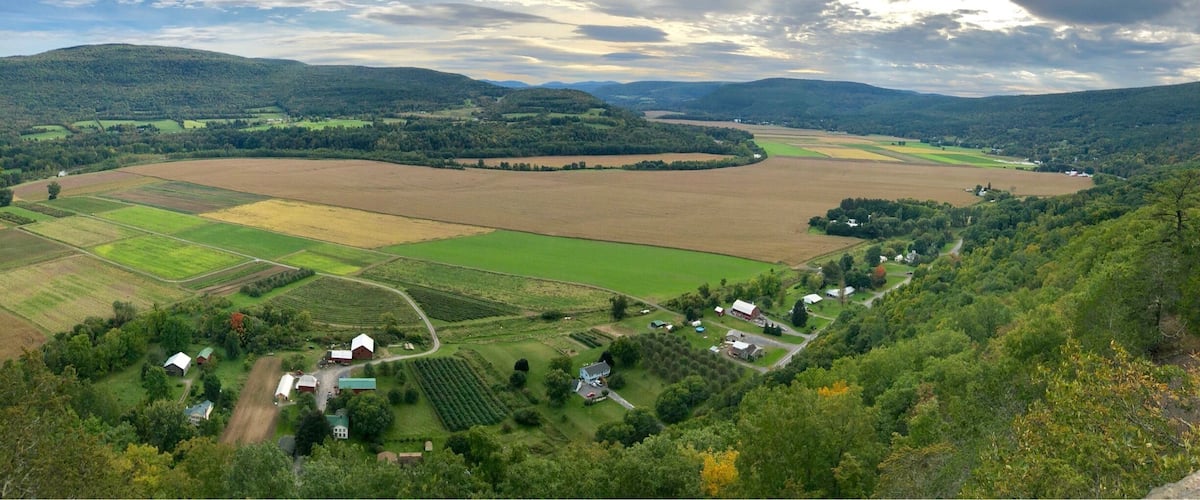 A rural landscape with fields, a winding road, and scattered houses.