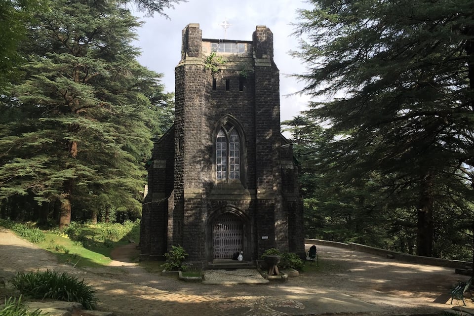 Une église historique en pierre, entourée d’une forêt dense.