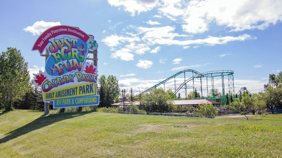 A sign for Catania Amusement Park with a roller coaster in the background.