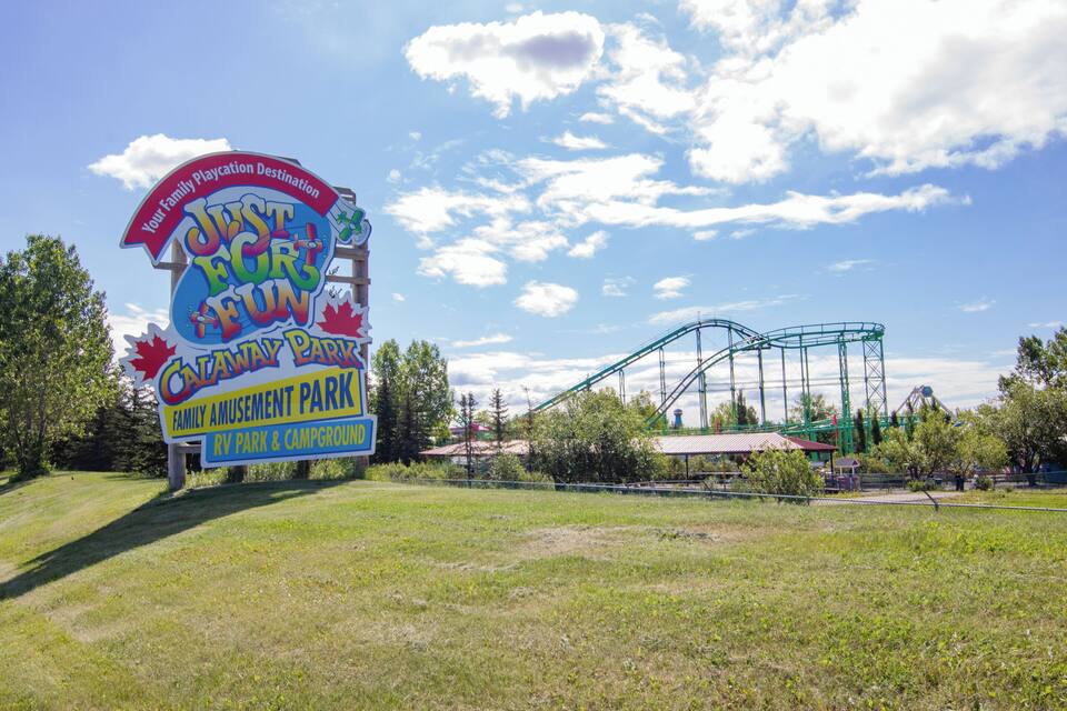 A sign for Catania Amusement Park with a roller coaster in the background.