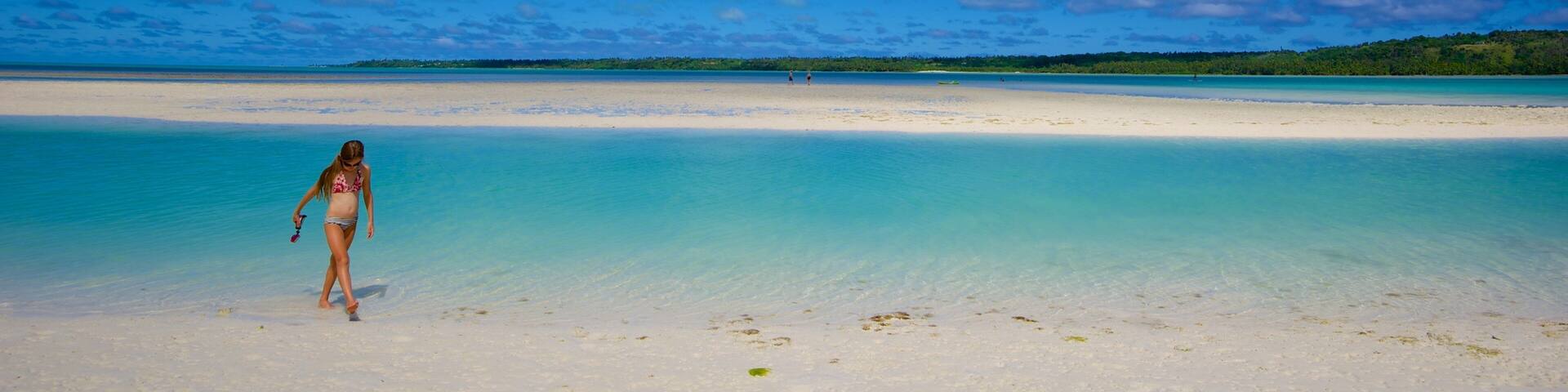 Aitutaki featuring a sandy beach as well as an individual femail