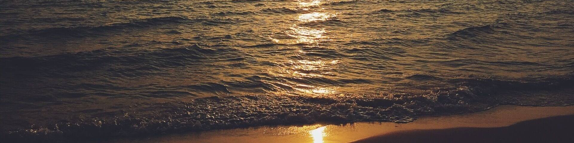 A sunset over the ocean with a boat on the water.