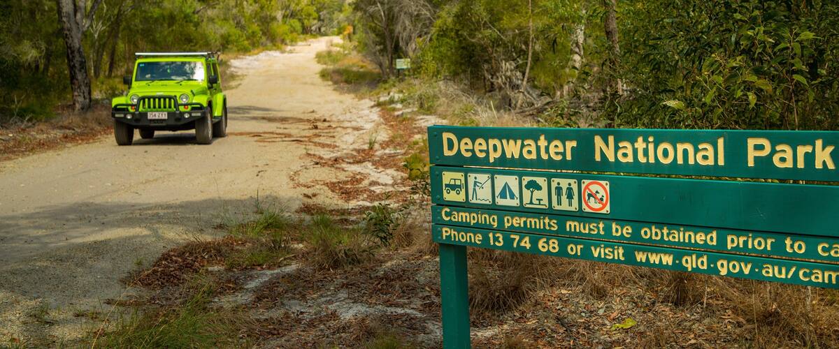 A green sign for Deepwater National Park with camping permits information.