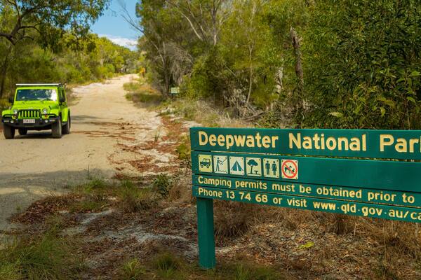 A green sign for Deepwater National Park with camping permits information.