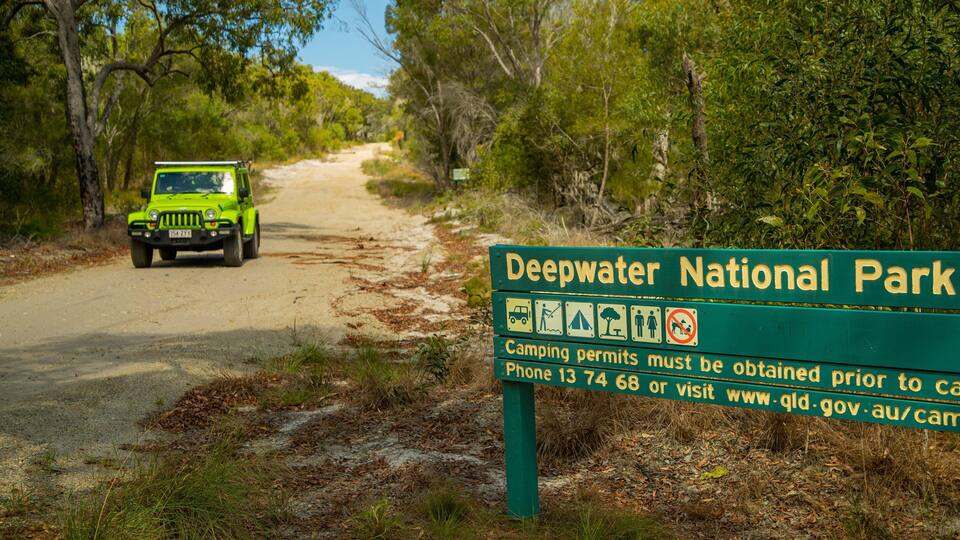 A green sign for Deepwater National Park with camping permits information.