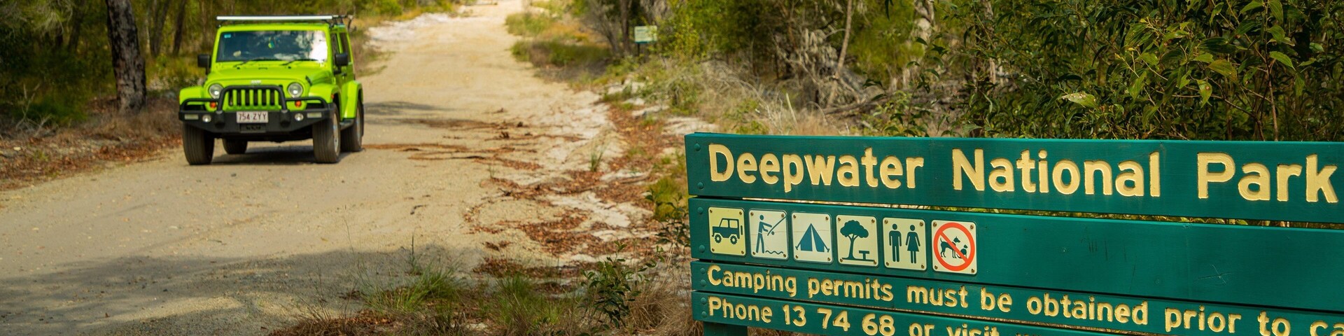 Señal verde del Parque Nacional Deepwater con información sobre permisos de acampada.