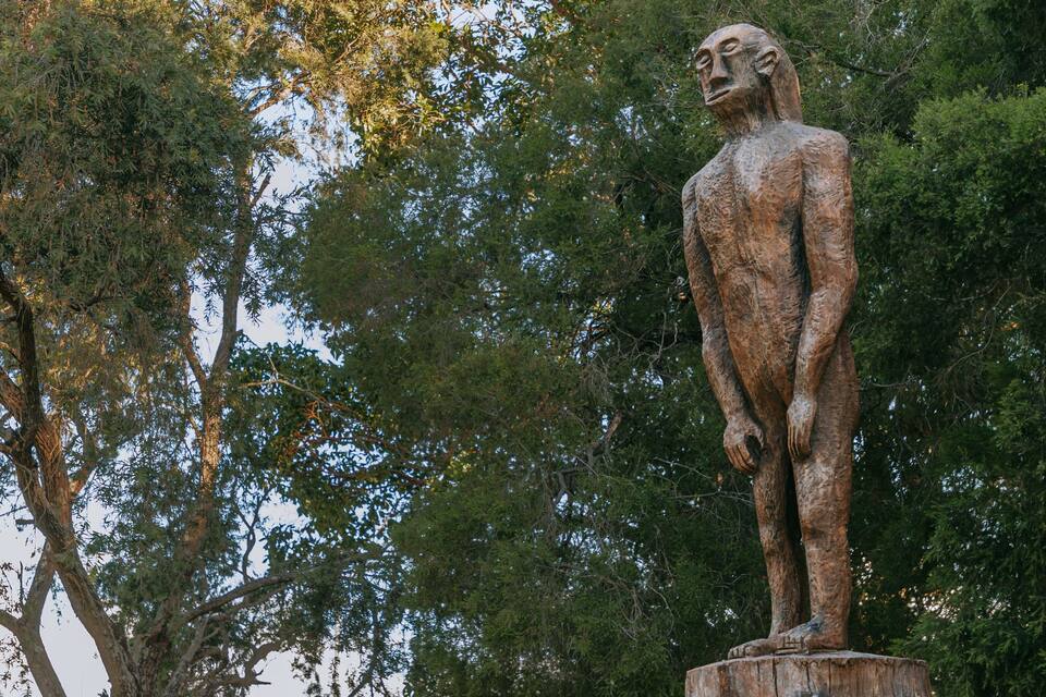 Uma estátua de bronze de uma figura humana sobre um toco de árvore.