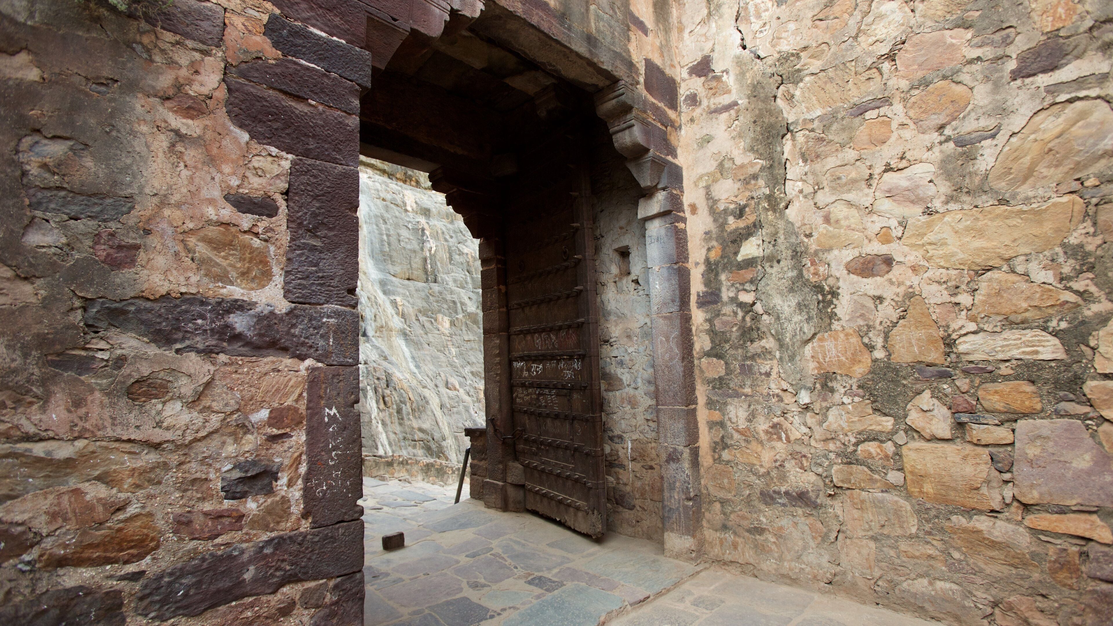 Un antiguo arco de piedra que da paso a una puerta de madera.