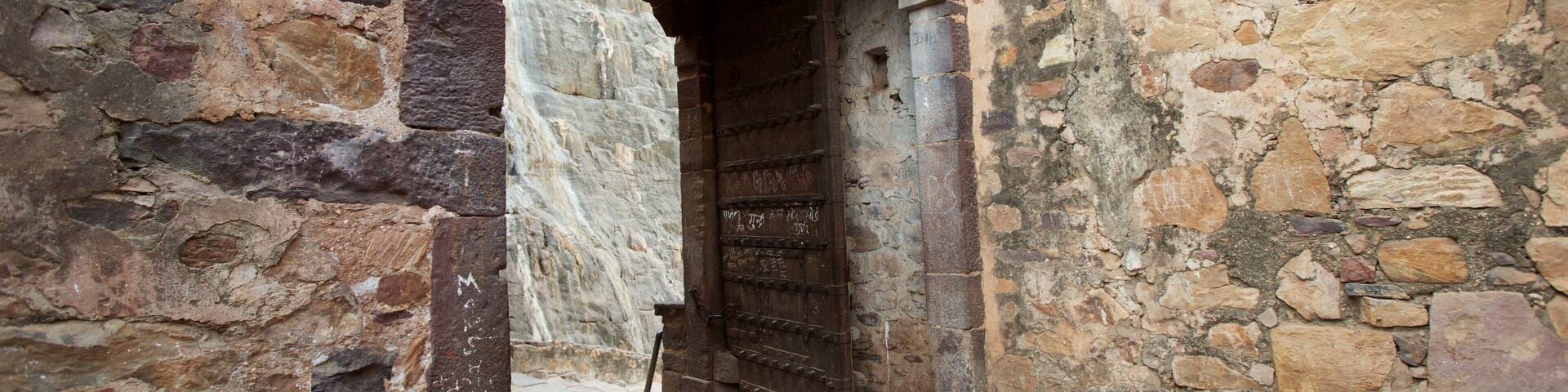 An ancient stone archway leading to a wooden door.