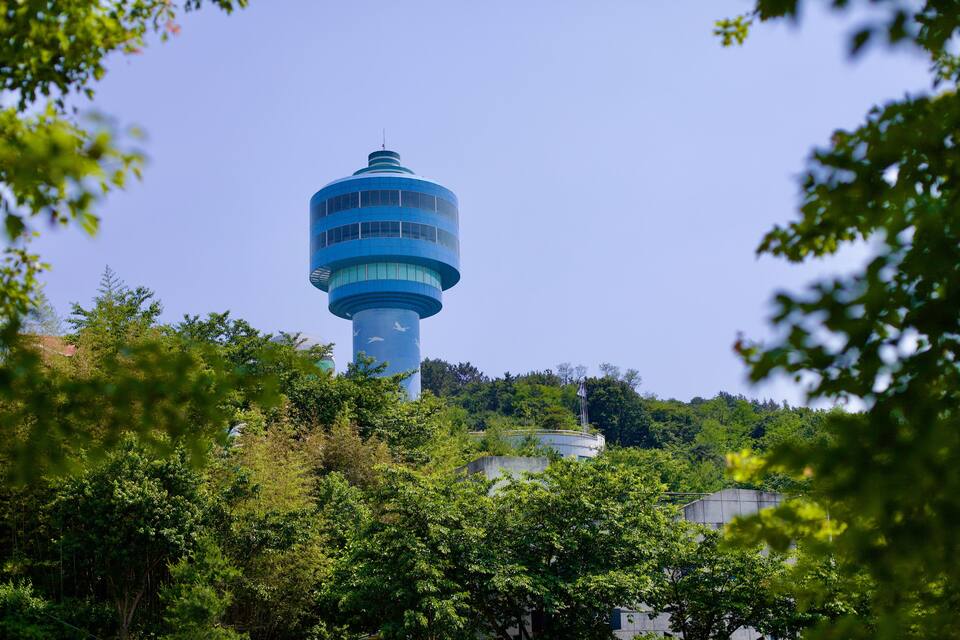 Ein blauer Turm, umgeben von üppigem Grün.