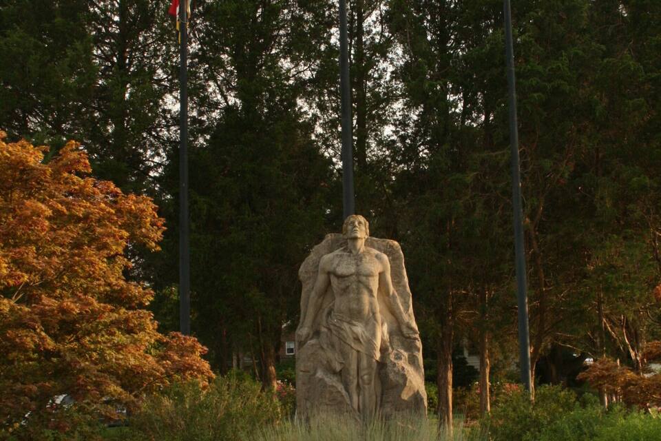 A statue surrounded by a garden with orange flowers and tall grasses.