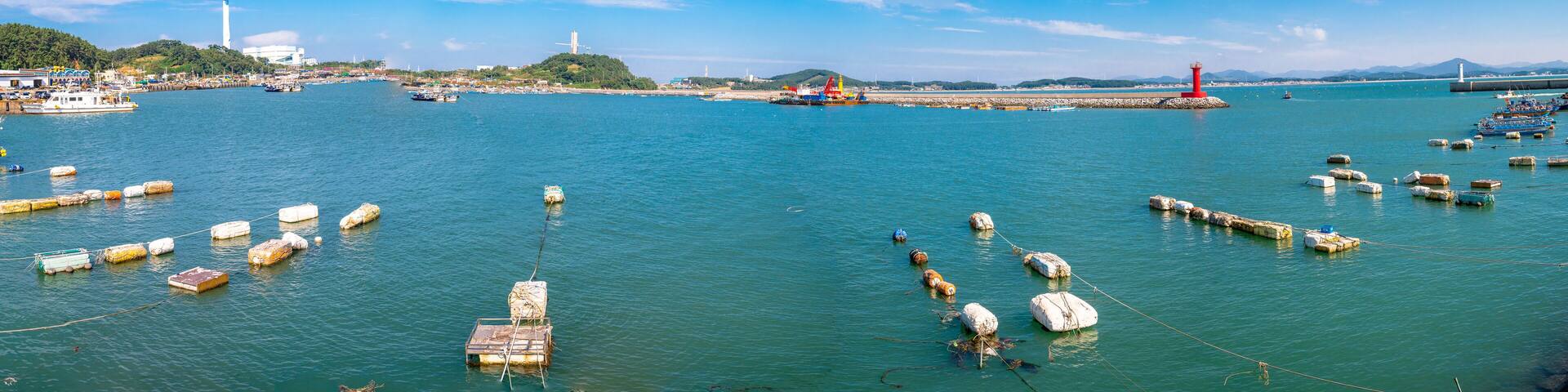 A harbor with boats, buoys, and a lighthouse.