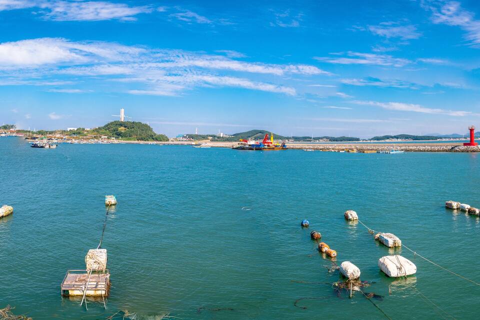 A harbor with boats, buoys, and a lighthouse.
