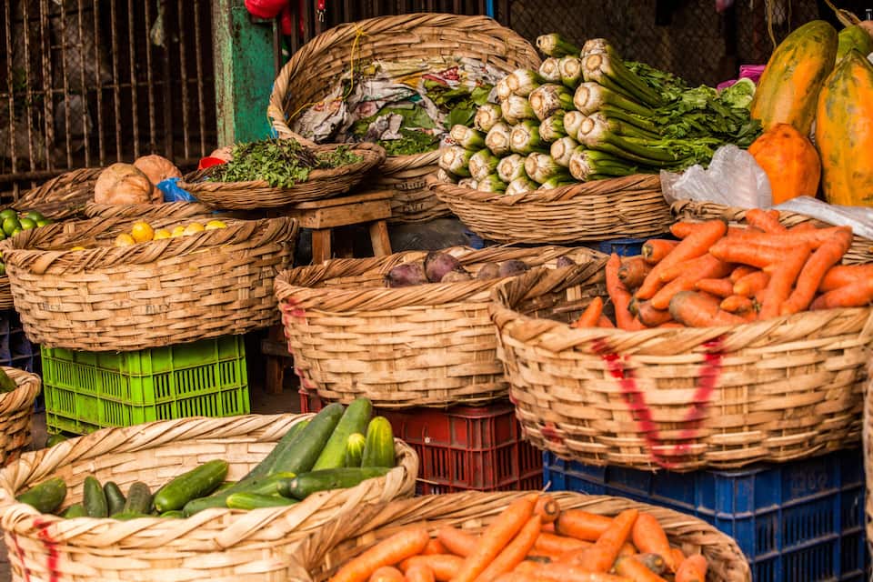 A variety of fresh vegetables displayed in baskets at a market.