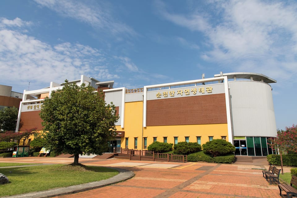 A modern building with a curved roof and a sign in a foreign language.
