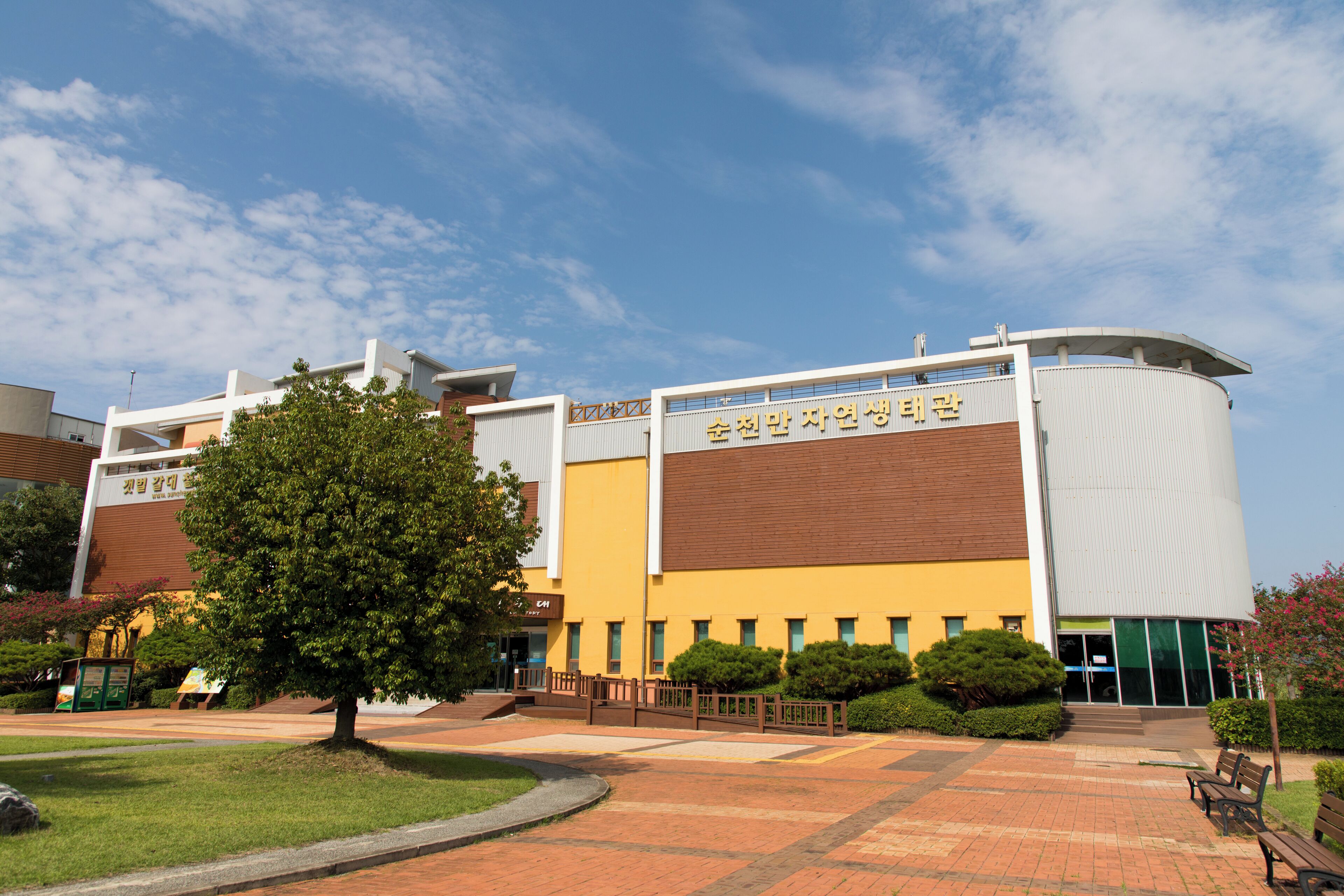 A modern building with a curved roof and a sign in a foreign language.