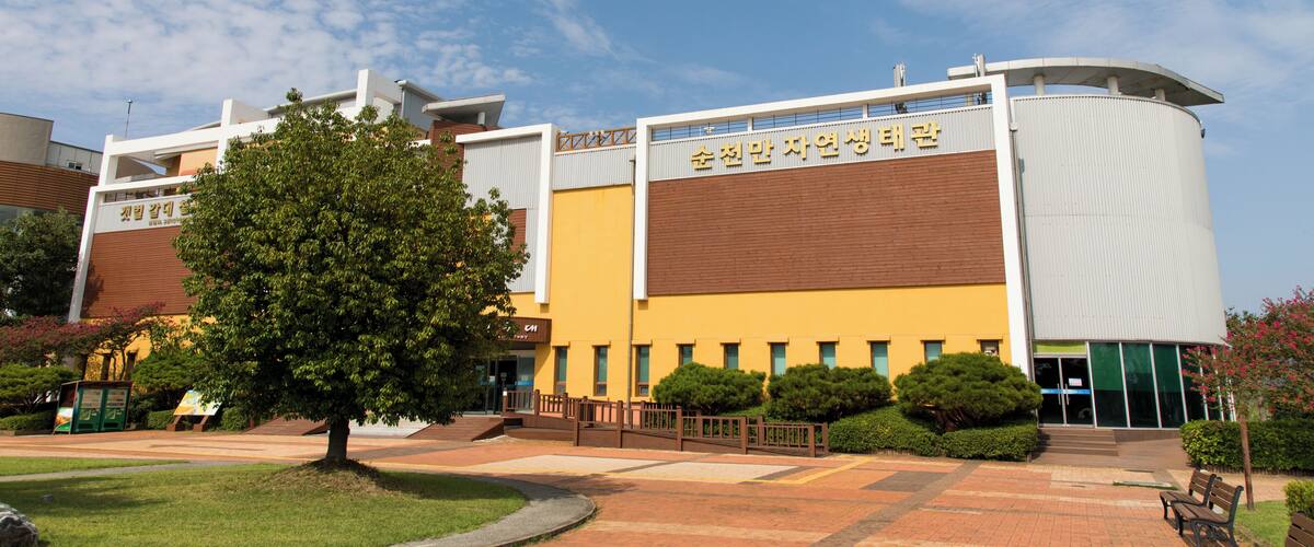 A modern building with a curved roof and a sign in a foreign language.