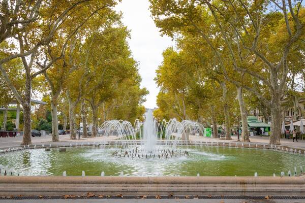 Une fontaine entourée d’arbres aux feuilles jaunes, dans un parc.