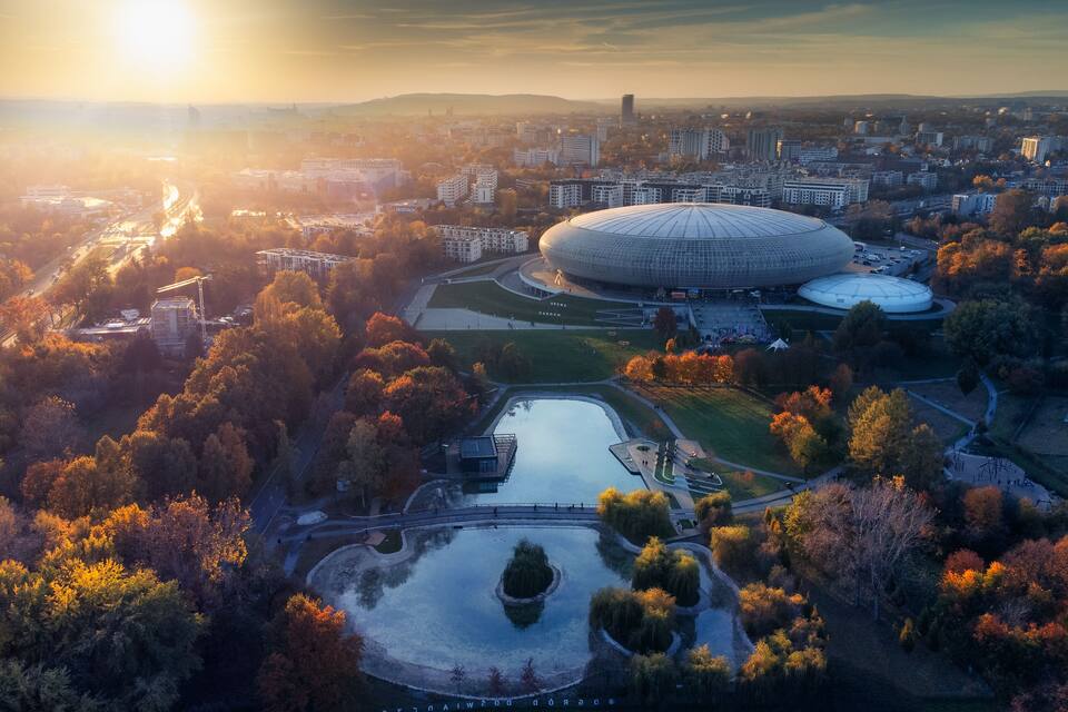 Vista aérea de un paisaje urbano que muestra un estadio grande, edificios circundantes y follaje otoñal.