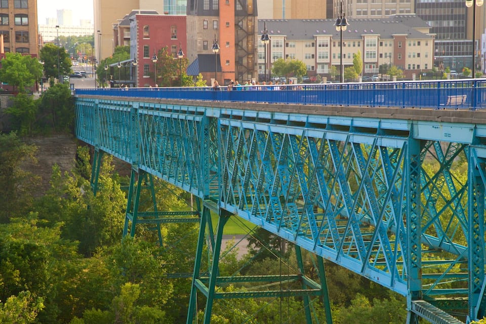 Eine blaue Stahlbrücke mit einer Stadtlandschaft im Hintergrund.