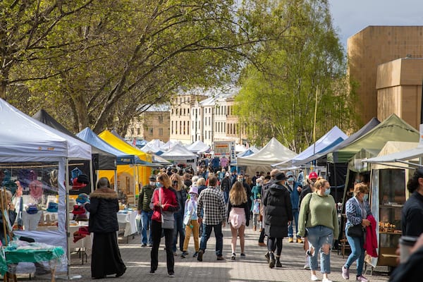 A busy outdoor market with various stalls and people walking around.