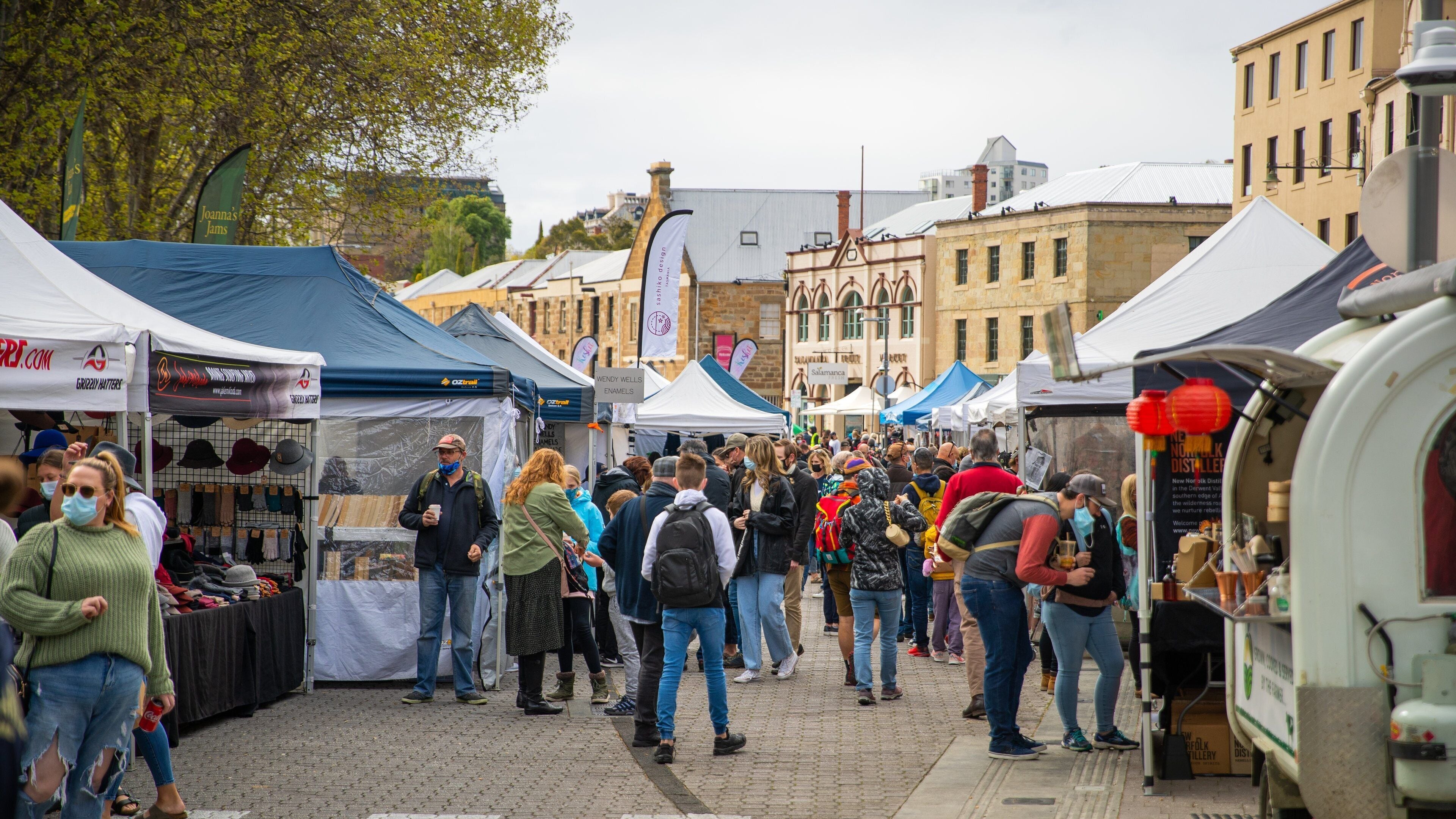 Un marché animé en plein air, avec de nombreux étals et tentes.