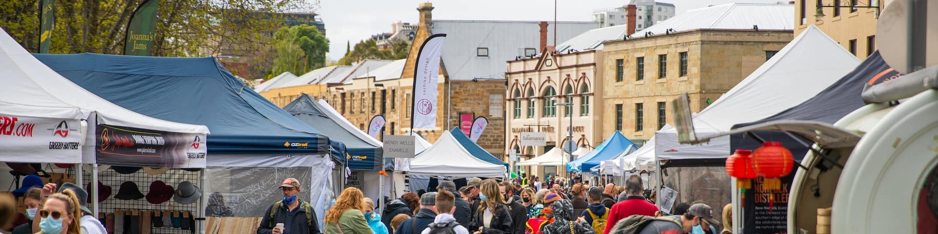 Un marché animé en plein air, avec de nombreux étals et tentes.