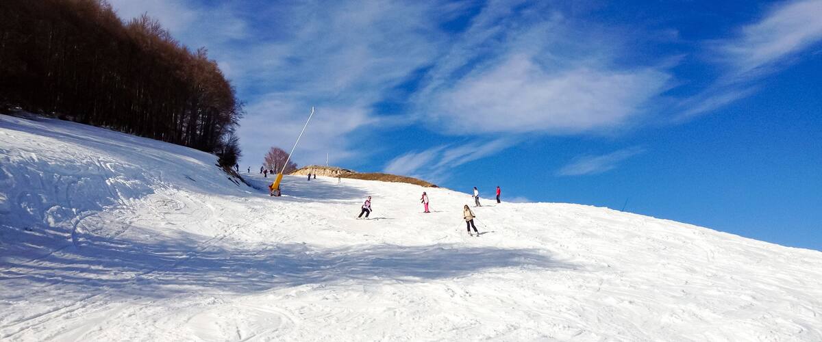 A snowy ski slope with skiers and a ski lift.