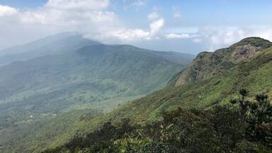 A mountainous landscape with lush green vegetation and a clear blue sky.