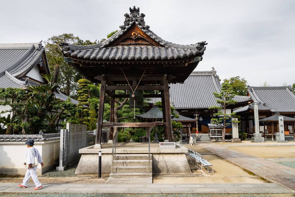 A traditional Japanese temple with a pagoda-style roof, surrounded by well-maintained gardens and stone pathways.