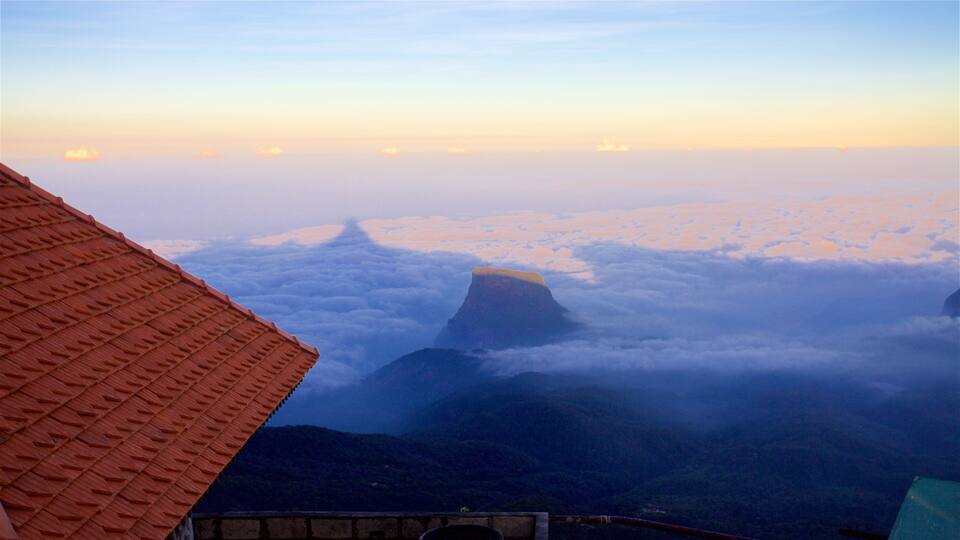 A mountain peak above clouds, a red-roofed structure, and a valley.