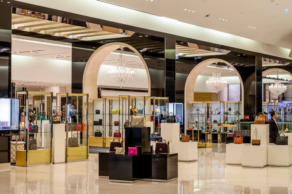 Une boutique de luxe vendant des sacs à main, avec des vitrines en verre et des lustres.